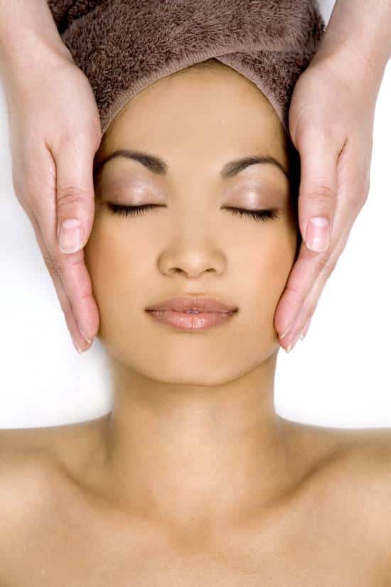 Hands performing a facial treatment.